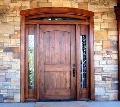 a wooden door sitting on top of a stone wall next to a brick entrance way