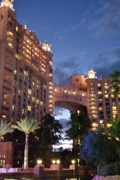 the hotel is lit up at night in front of palm trees and water features lights