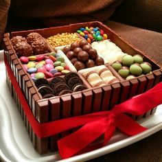 a chocolate box filled with lots of different types of candy and candies on top of a white plate