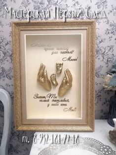 there is a framed picture with two baby feet in gold shoes on the table next to a plate