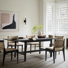 a dining room table with four chairs and a vase on the table next to it