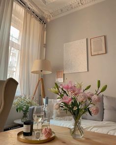 a living room filled with furniture and flowers on top of a wooden table in front of a window