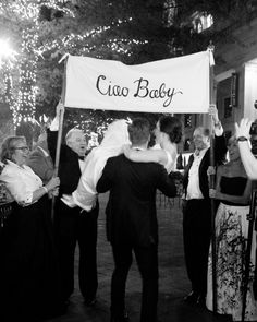 a group of people standing around each other holding a sign that says ciao baby