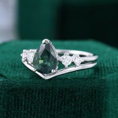 a close up of a ring with a green stone in it on top of a green cloth