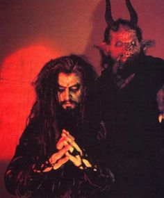 two men dressed up as devil and demon with horns on their heads, standing next to each other