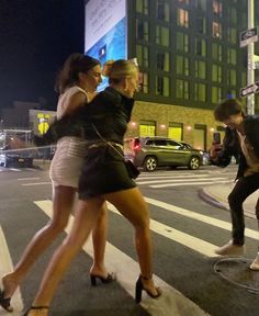 two young women crossing the street at night