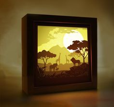 a shadow box with an image of giraffes and trees in the background