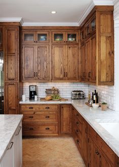 a large kitchen with wooden cabinets and marble counter tops, along with white subway backsplash