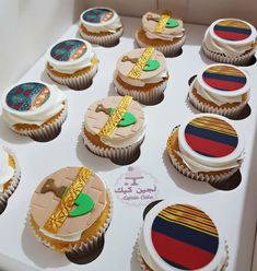 twelve decorated cupcakes in a box with flags and ribbons on them are ready to be eaten