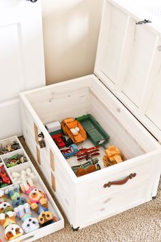 an open toy chest on the floor with toys in it