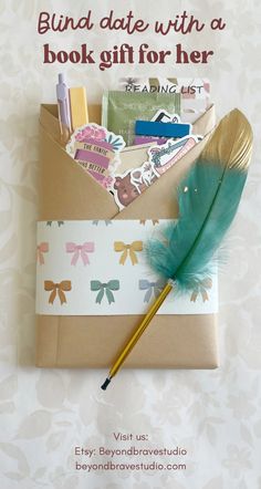 an envelope with a feather, pen and notepad on it that says blind date with a book gift for her