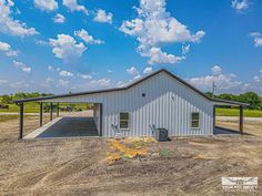 a white building sitting on top of a dirt field next to a blue cloudy sky