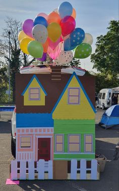 a house made out of cardboard with balloons on top