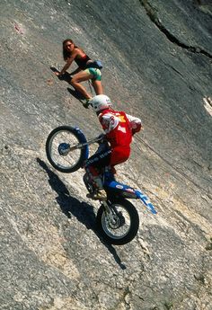 a man riding on the back of a dirt bike down a rocky slope next to a woman