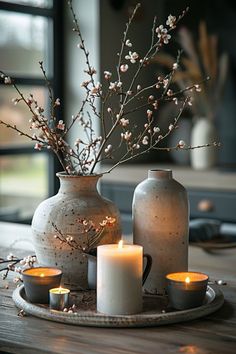 two vases with flowers and candles on a table