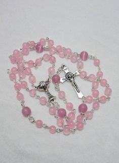 This pink First Communion rosary for girls is made with 6mm pale pink agate rounds and 8mm matte pink cat's eye beads. It measures about 27 inches around the body and has a 5 inch cross drop. The crucifix and the chalice are Italian made oxidized silver. I hand turned the silver plated wires. This rosary will be slipped into a velvet bag and shipped in a bubble mailer. Pink Rosary With 8mm Round Beads, Catholic Communion, Catholic Rosary, Matte Pink, Rosary Catholic, Pink Agate, Eye Beads, Bubble Mailer, Pink Cat