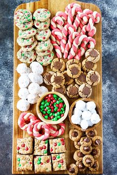 a wooden platter filled with lots of different types of cookies and candies on top of each other