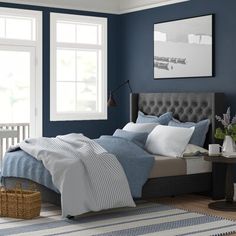 a bedroom painted in blue and white with a bed, nightstands, window, rug and basket