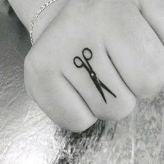 black and white photograph of a person's hand with scissors tattoo on the middle finger