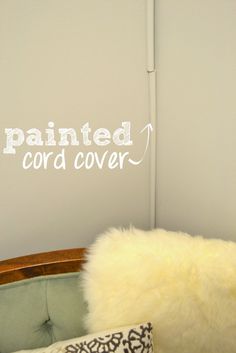 a chair with a pillow on top of it next to a wall that says painted cord cover