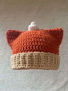 an orange and white crocheted pillow hanging from a hook