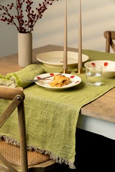 the table is set with plates and glasses on it, along with flowers in vases