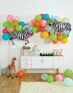 a party with balloons, zebras and giraffes on the wall above a buffet