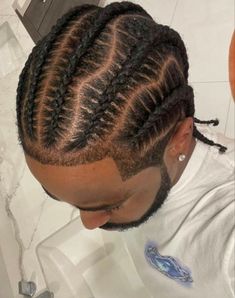 a man with long cornrows and braids on his head sitting in front of a sink