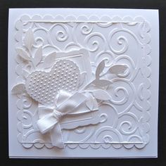 a white greeting card with a bow and heart on the front, made out of paper