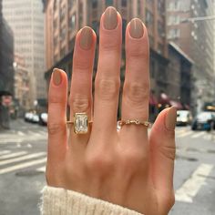 a woman's hand with an engagement ring on it, in the middle of a city street