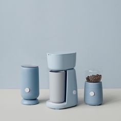 three different types of coffee makers sitting on a white table with blue walls in the background