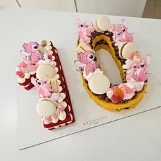 two donuts decorated with pink and white decorations on top of a table next to each other