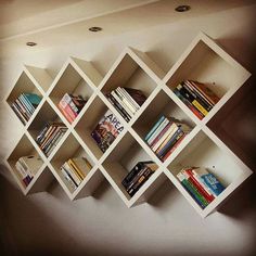 the bookshelf is made out of white cubes and has several different types of books on it