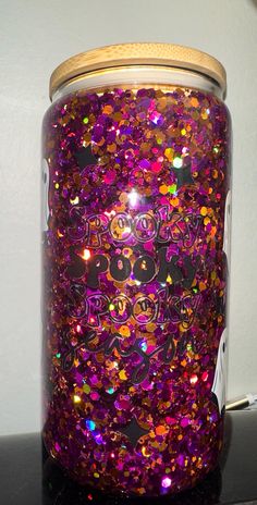 a jar filled with glitter sitting on top of a black counter next to a white wall