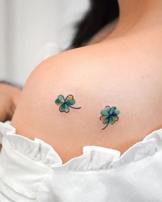 two clover tattoos on the back of a woman's shoulder