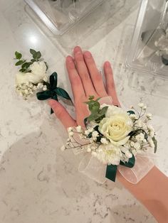 a person's hand with flowers and greenery on it