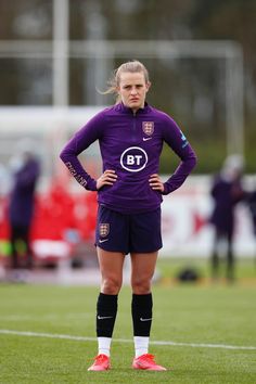 a female soccer player is standing on the field with her hands on her hips and looking at the camera