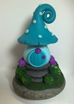 a small blue mushroom house sitting on top of a rock