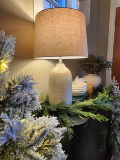 a lamp is sitting on top of a table with evergreen branches and other christmas decorations