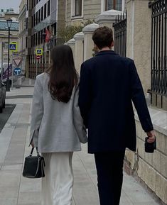 a man and woman walking down the street holding hands