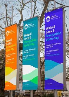 three colorful banners hanging from the side of a pole