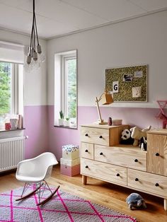 a child's room with pink and white walls, wooden furniture and toys on the floor