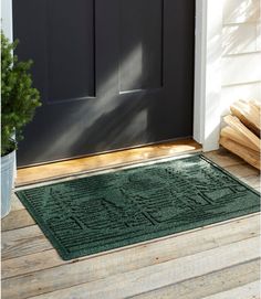 a green door mat sitting on top of a wooden floor next to a potted plant