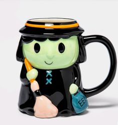 a black and green ceramic mug with a character holding a bag