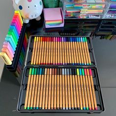 there are many colored pencils in the tray on the table next to each other