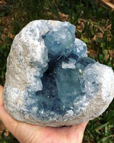 a person holding up a rock with blue crystals on it's side in their hand