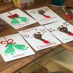 christmas cards with handprints on them sitting on a table next to markers and pens