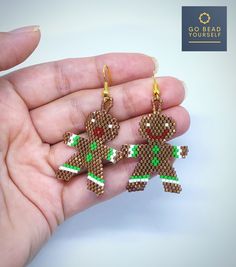 a hand holding two christmas themed gingerbread earrings