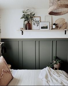 a bedroom with green paneled walls and plants on the shelf above the headboard