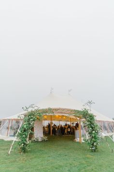 a large tent with greenery on the side and people standing in it at the front